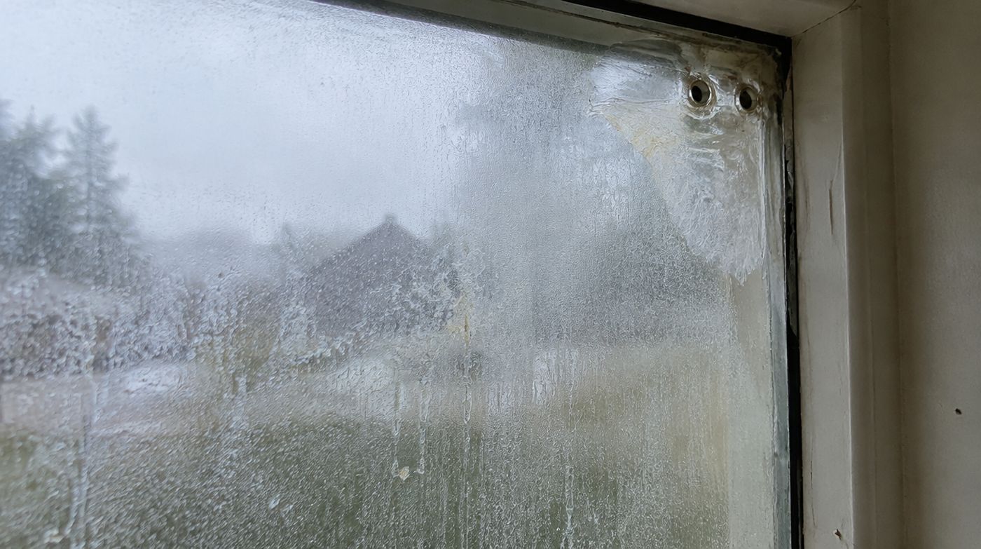 A misted pane with two small drilled vent holes in the corner, a crude attempted repair